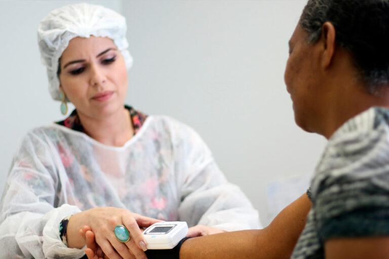Uma médica mede pressão de uma senhora. Imagem representa a saúde da população de São Paulo